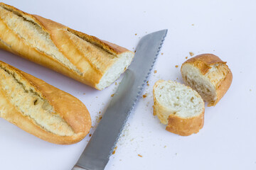 Fresh baguette breads on white surface with knife,sliced.