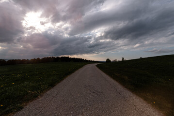 Curved country road through rural pastures at Rosenheim, Bavaria, Germany (During sunset).

