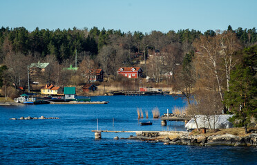 Picturesque summer houses painted in traditional falun red on dwellings island of the Stockholm archipelago in the Baltic Sea in the early morning.