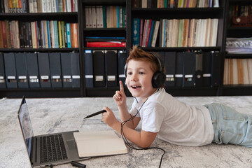 Toddler boy using laptop and headphones for online / destination education. Getting new knowledge from internet at home.