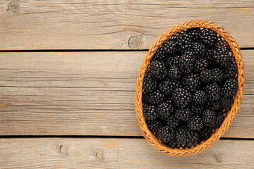 Blackberry in a wicker basket on a grey wooden background. Blackberry close up.
