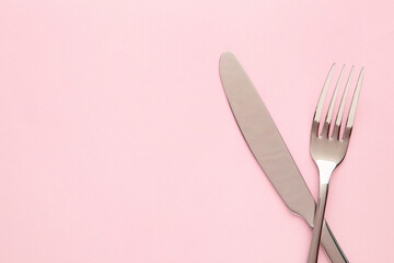 Fork and knife with copy space on a pink background