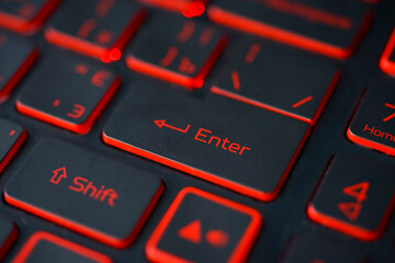 Red backlit computer keyboard macro shot of enter key