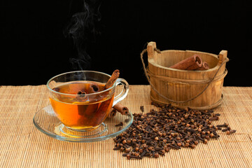 Obraz na płótnie Canvas hot cinnamon tea and clove grains on tree table