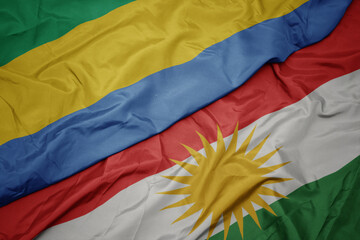 waving colorful flag of kurdistan and national flag of gabon.