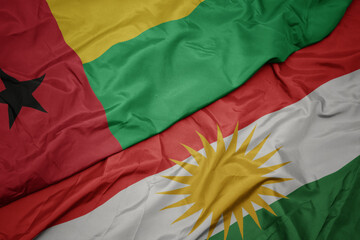 waving colorful flag of kurdistan and national flag of guinea bissau.