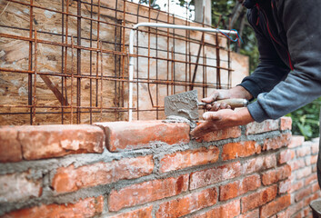 Construction bricklayer worker building brick walls with mortar, trowel. Industry details