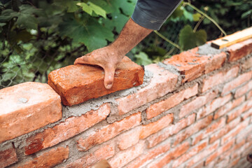 industrial Construction bricklayer worker building walls with bricks, mortar and trowel
