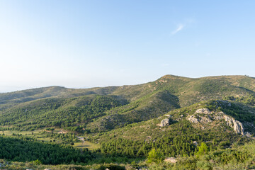 A landscape of mountains surrounded by hills and a path on a sunny day