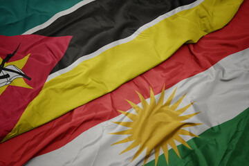 waving colorful flag of kurdistan and national flag of mozambique.