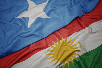 waving colorful flag of kurdistan and national flag of somalia.