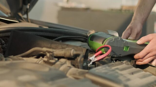 Auto service worker checking voltage on car battery. Service engineer working in car service station
