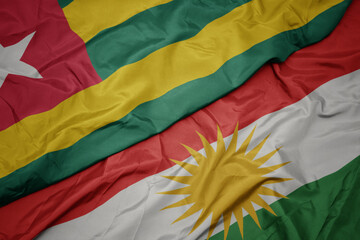waving colorful flag of kurdistan and national flag of togo.