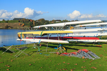 Obraz na płótnie Canvas Racing boats on the grassy shore of a lake. Photographed at Lake Karapiro, New Zealand, one of the country's premiere rowing venues