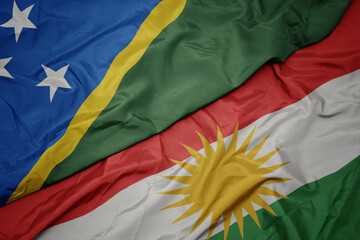 waving colorful flag of kurdistan and national flag of Solomon Islands .