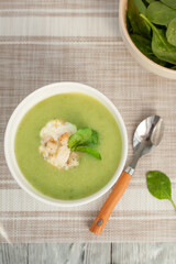 Green cream soup in a white bowl with spinach leaves. The view from the top.Delicious spinach soup for a healthy lifestyle