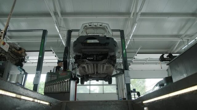 Auto mechanic working underneath car lifting machine at the garage. Auto repair shop, Car service, repair.    