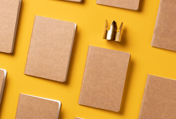 content is king for online marketing concept.top view of notebook with golden crown align with kraft paper book in pattern on yellow table background