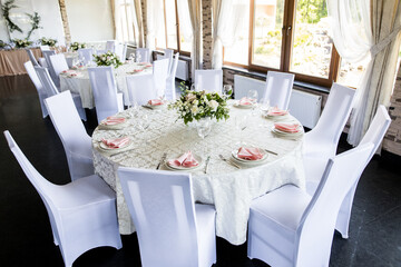 Festive table setting with wine glasses, and fresh flowers. Selebration banquet with pink napkins, white plates and wineglasses in restaurant