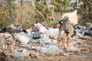 A poor boy collecting garbage waste from a landfill site in the outskirts. Poverty and child labor concept, human trafficking.