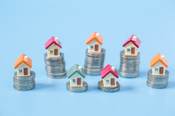 Mini house on stack of coins on blue  background. Concept of Investment property and Risk...