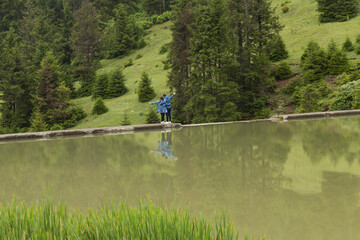 The couple reflection on the lake. They are looking at the forest.