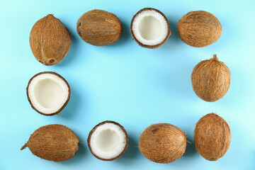 Top view shot of coconuts, whole and cracked on halves on paper textured background with a lot of copy space for text. Background with raw fruit of tropical palm. Flat lay.b