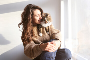 Charismatic young woman playing with her adorable cat.