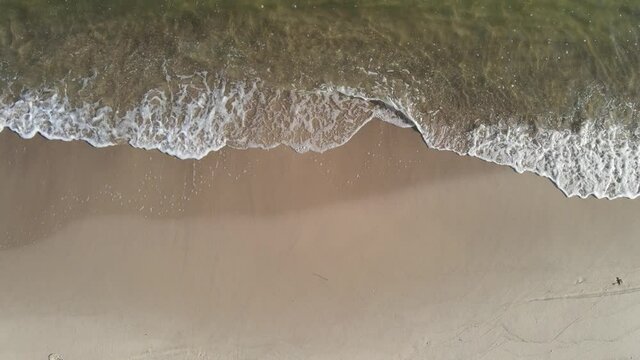 Aerial view of the gentle waves crashing on the sandy beach on the Baltic Sea