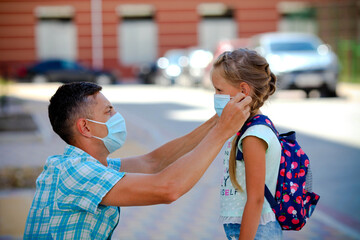 Obraz premium The father puts a surgical masks on his daughter is face.