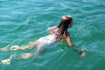 girl swims in the sea, back view .