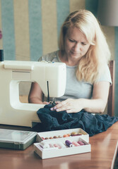 A woman at home works on a sewing machine, a woman at home sews on a sewing machine