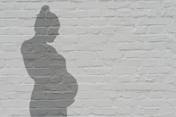 Ein Schatten einer schwangeren Frau an einer weißen Wand