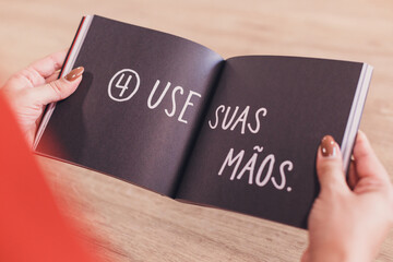 Open book, black book, book page, person holding book, reading, big print, reading legible letters, to study, person studying, learning to read