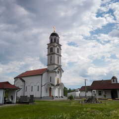 Fototapeta na wymiar The village church in Bosanski Lužani dedicated to All Saints against the cloudy sky during the day. A temple building of simple architecture.
