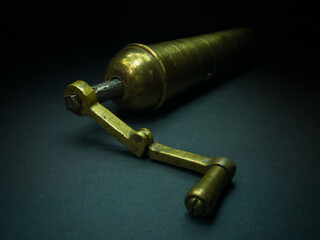 Traditional Turkish brass grinder for roasted coffee for the best aroma isolated in the dark on a dark background. Retro antique portable hand-held coffee mill, kitchen equipment.