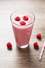 Raspberry smoothie in glass on wooden table