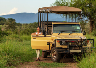 Girl standing close to a safari car, during a coffee stop of a safari drive in the wilderness of Africa © rmferreira