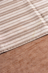 Mantel de rallas sobre mesa de madera en tonos cafes. Tela puesta en diagonal sobre mesa para comer.