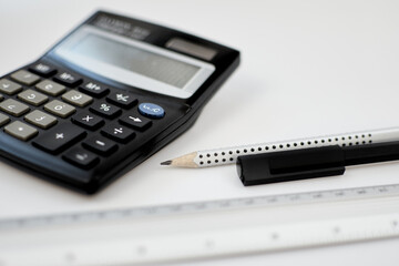 Close-up view accounting calculator white office desk table near pen, pencil, measuring scale and other office supplies
