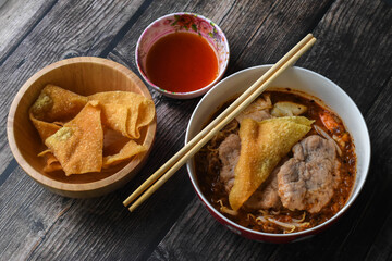 Top view of Spicy lemongrass flavored noodle soup with marinated pork chops and fried wontons (side dish)