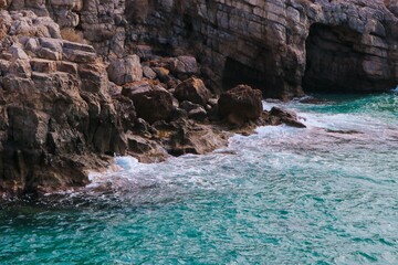 blue sea hitting the rocky coast, cave in the sea