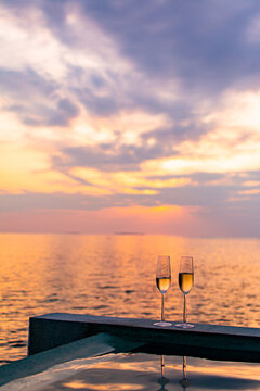 Enjoying two glasses of champagne in a pool watching sunset in the ocean