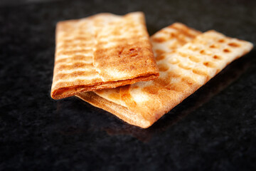 Two ruddy cookies on black marble. Freshly baked product. Selective soft focus.