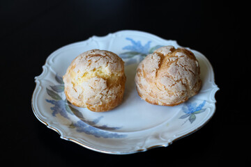 Scones with whipped cream on a white, antique, German, porcelain plate with a gold border and blue flowers on a black background...