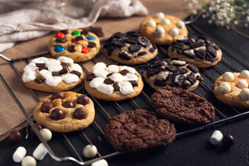 galletas hechas en casa sobre una rejilla  de horno en un fondo negro con telas de cocina y dulces sobre ella