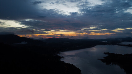 Aerial view of an amazing Colorful and Dramatic sunrise. Majestic Sunlight Cloud fluffy,Idyllic Nature Peaceful Background,Beauty Dark Blue Hour on Dusk,Purple Dawn Silhouette mountain on Kenyir Lake.