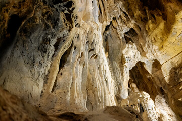 Stalactite and stalagmite formations on the rocky walls of a large underground cave.