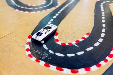 Miniature toy cars traveling along a road, children play.