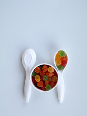 Sweet mixed color jelly candy in a white spoon against white background with copy space
